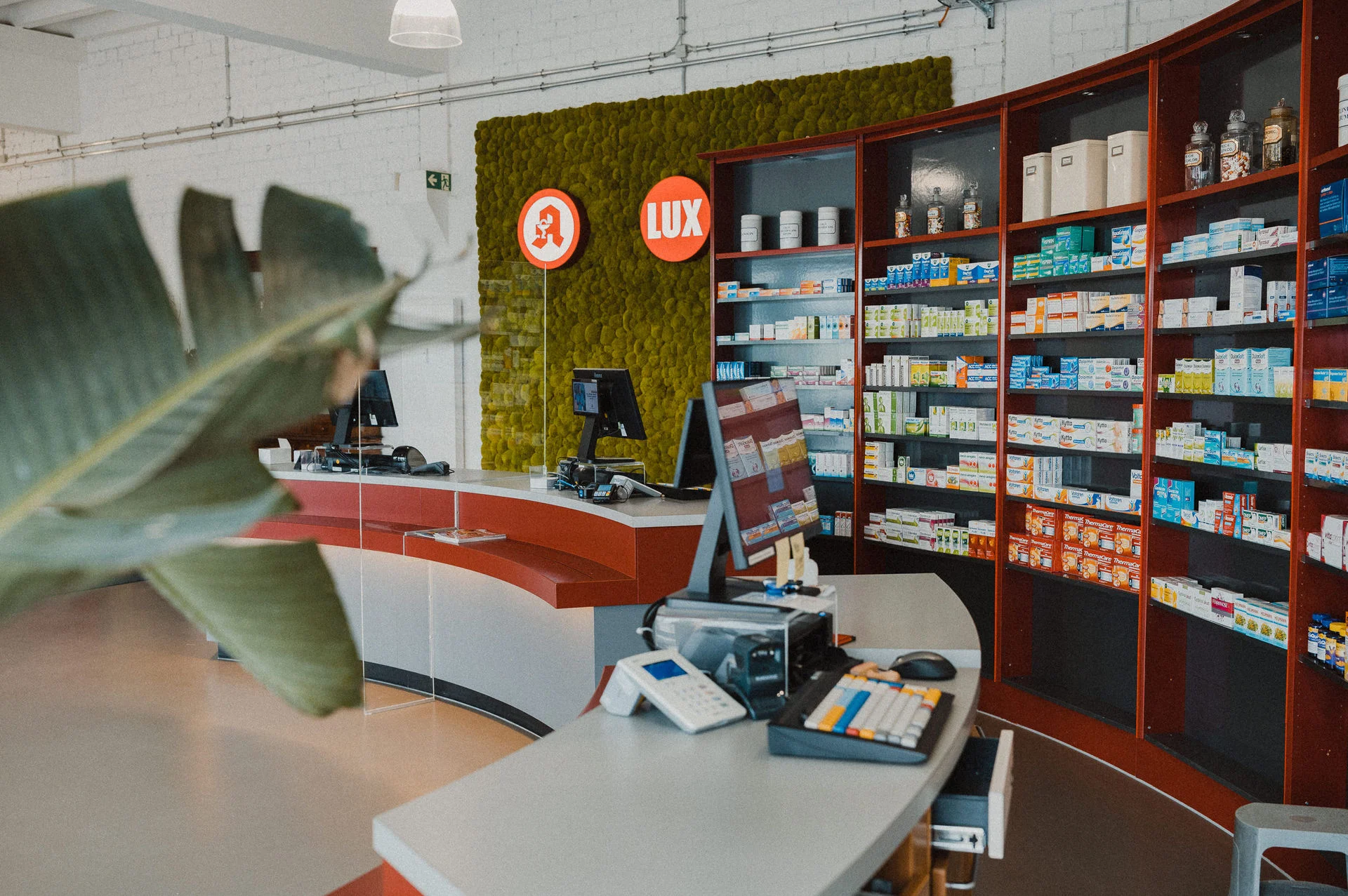 Übersicht über den Verkaufsraum der Apotheke. Im Vordergrund befinden sich die Beratungs- und Verkaufsplätze mit Computern, im Hintergrund die übersichtlich angeordneten Sichtwahlregale mit Arzneimitteln und Gesundheitsprodukten. Die moderne und offene Gestaltung unterstützt eine angenehme Beratungsatmosphäre.